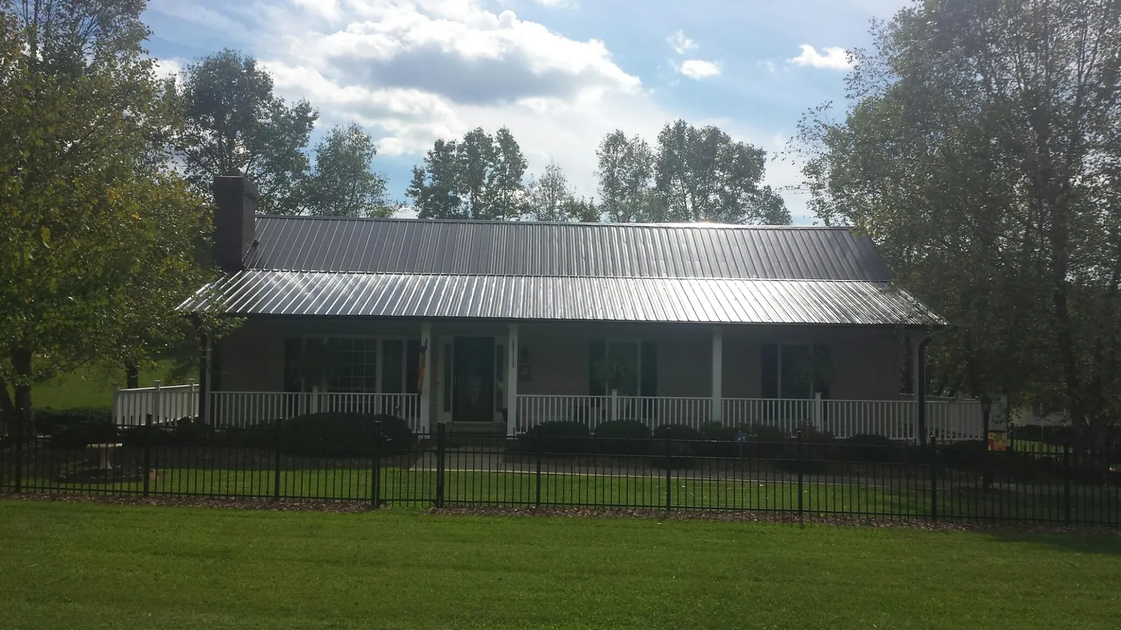Gray metal roof on a brick ranch with a full width front porch — Gutter Guard Installation work by our crew in Pine Hill