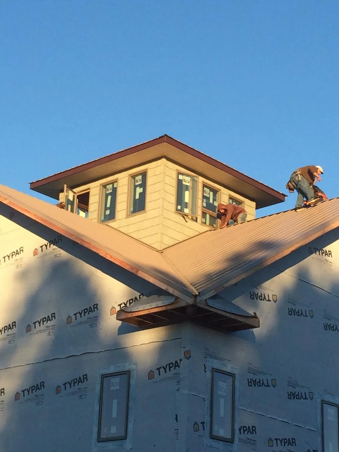 Roofers working around a rooftop cupola on a new metal roof at sunset — Roof Waterproofing in Pine Hill by Roofing Brothers